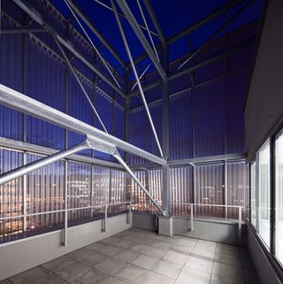 A closed terrace with metal construction and panoramic windows at night.