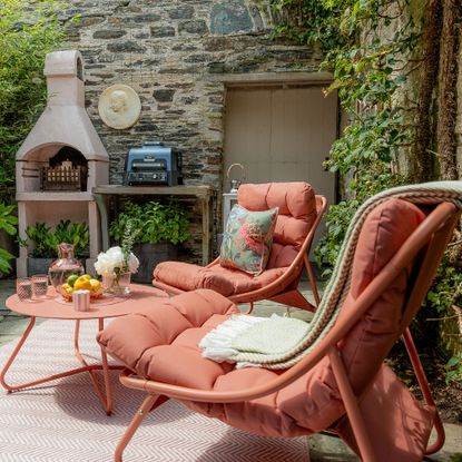 Pink seating area with loungers, coffee table and rug in Anouska Lancaster's walled garden outdoor kitchen area