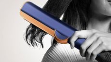 A woman using a Dyson hair straightener.