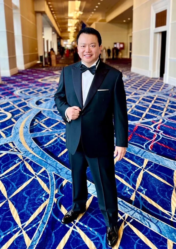 a man pictured in a ballroom wearing a suit