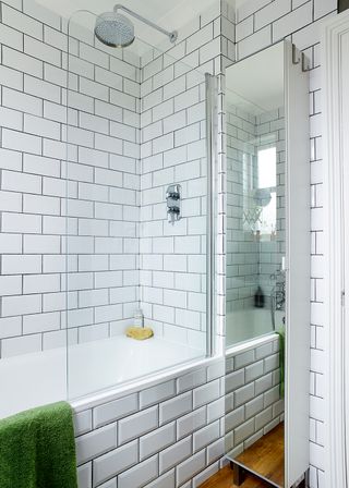 Curved bath screen in a white tiled bathroom