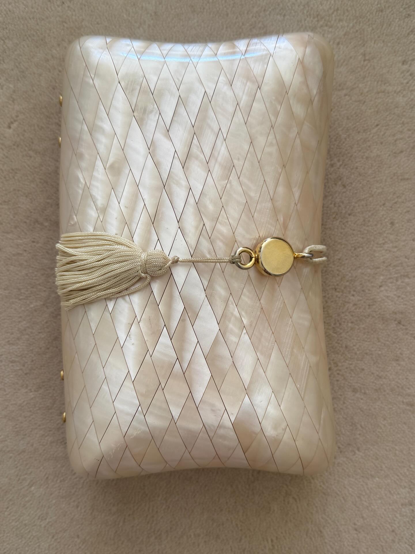 An image of a pearl clutch with tassel charm.
