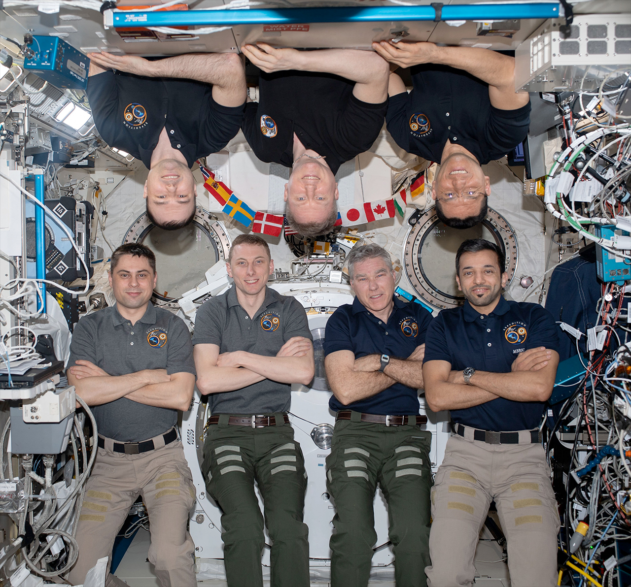 seven people float aboard the international space station, three of them upside down.