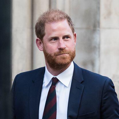 Prince Harry looking up to the right and wearing a blue suit