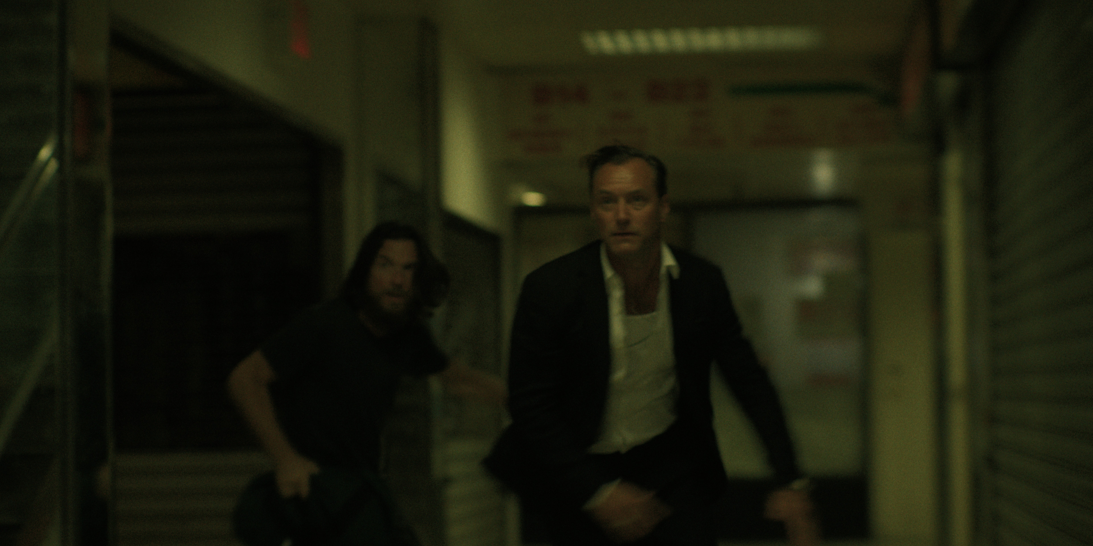 jason bateman and jude law as brothers vince and jake running down a hallway in black rabbit