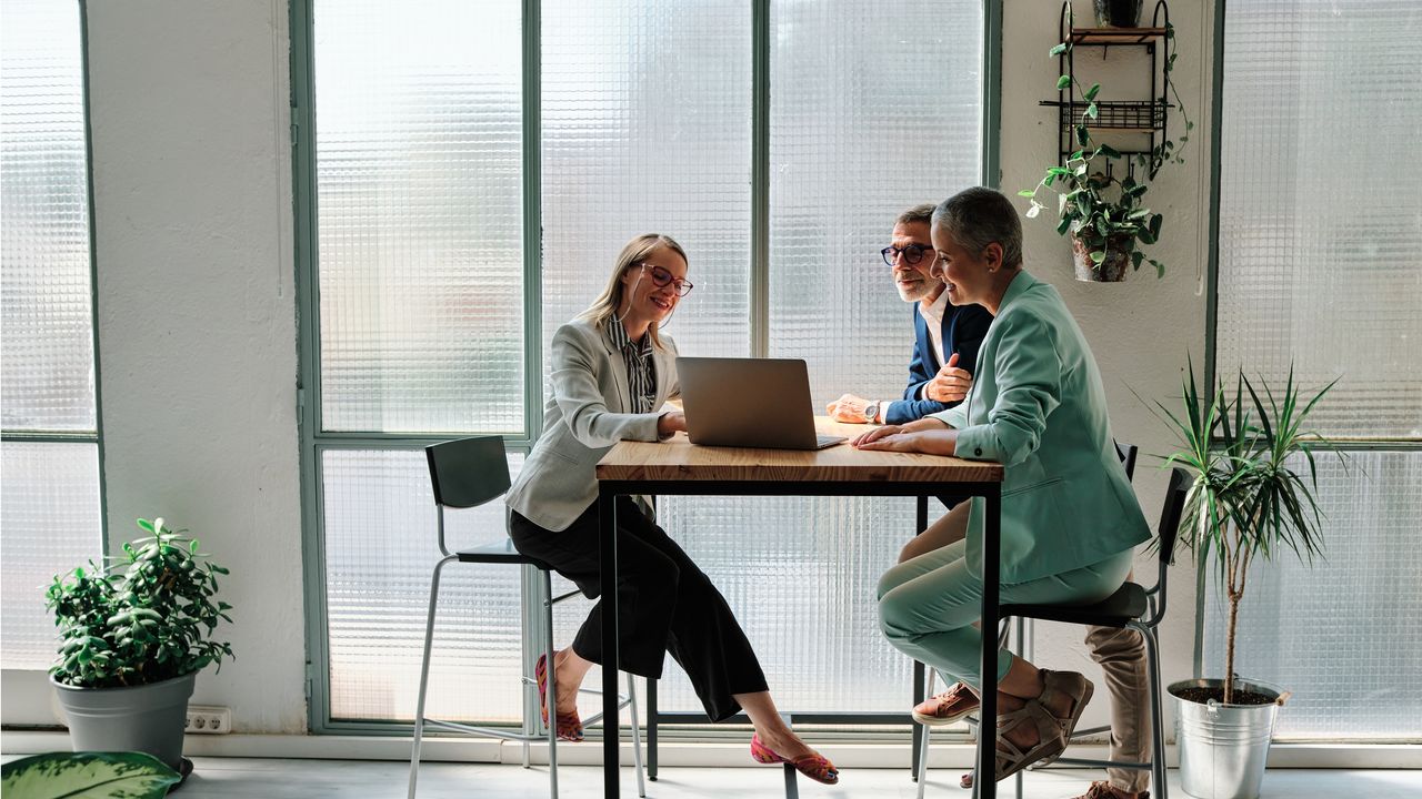 The employee of a financial institution meets with a couple at a bank branch.