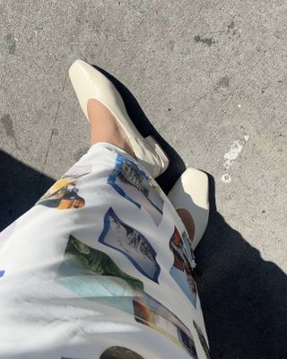 Woman wearing white printed maxi skirt with white Sam Edelman shoes.