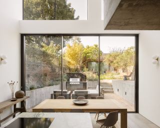 A minimalist kitchen with huge glass doors overlooking a lush garden