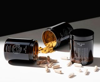 Nue Co powder and supplement pills in brown glass bottles on tabletop