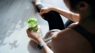 Woman holds green protein shake
