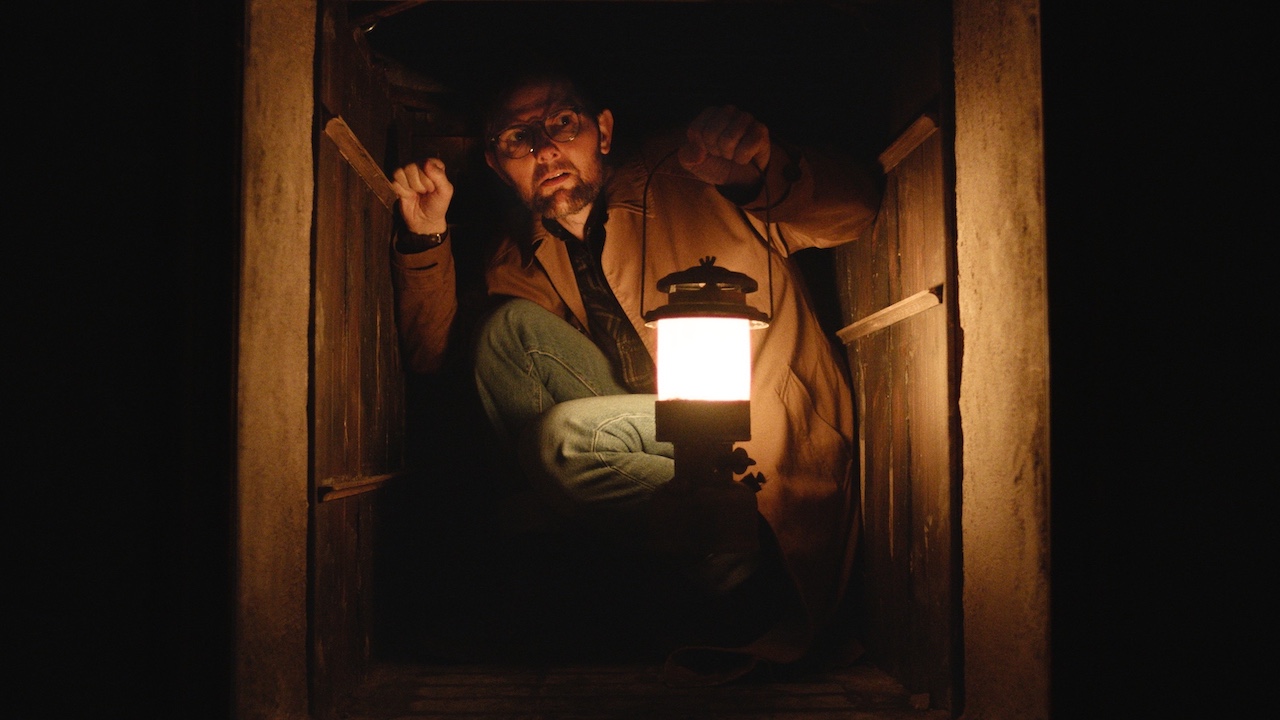 Adam Scott with a lamp in a tight space in Hokum