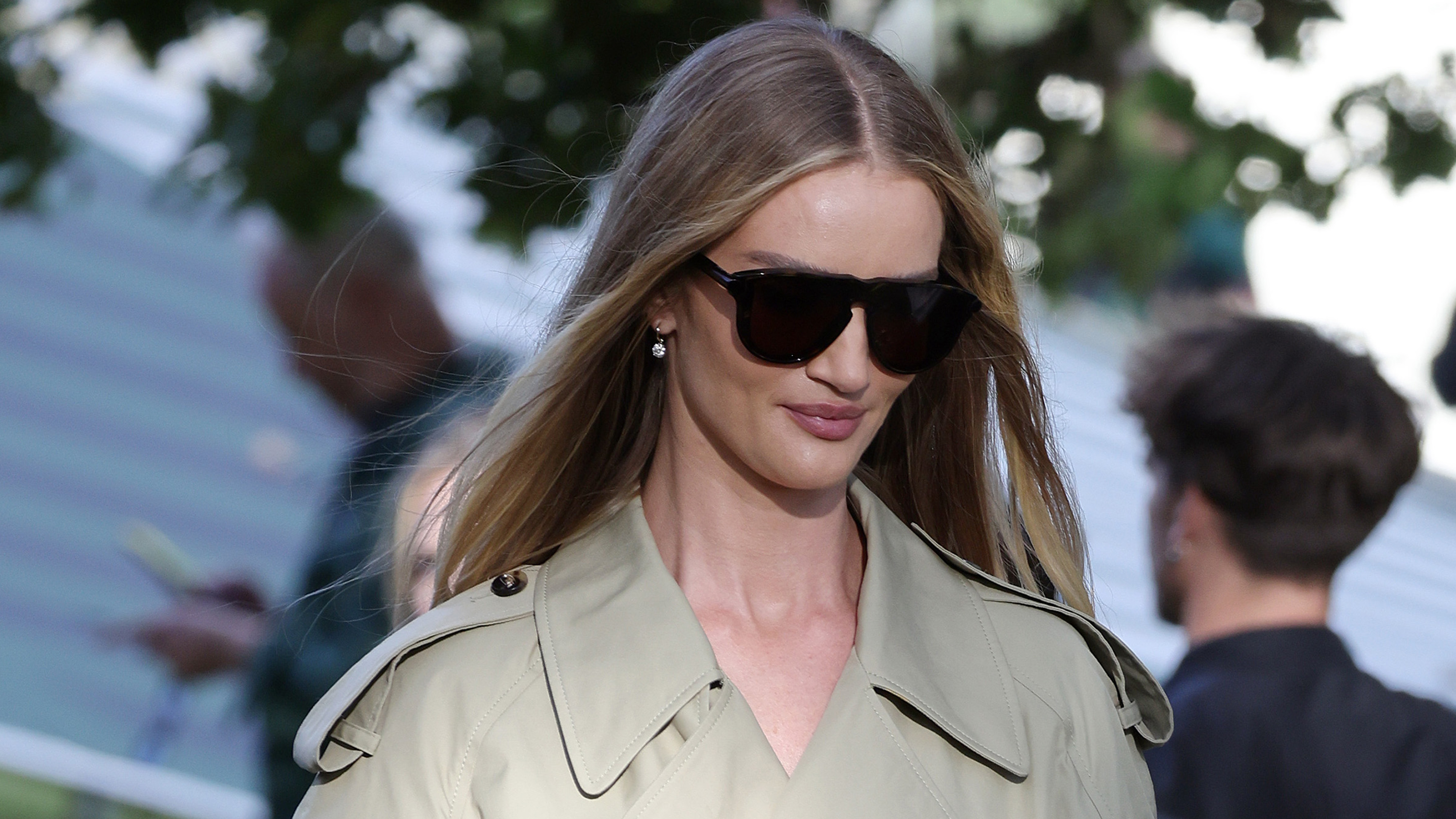 Rosie Huntington-Whiteley wears large sunglasses and a trench coat.