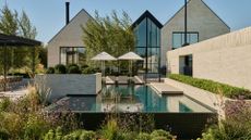 A large outdoor space with a pool, a garden, and outdoor parasols