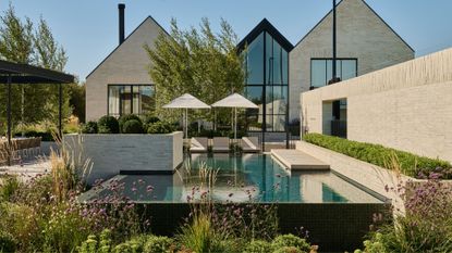 A large outdoor space with a pool, a garden, and outdoor parasols