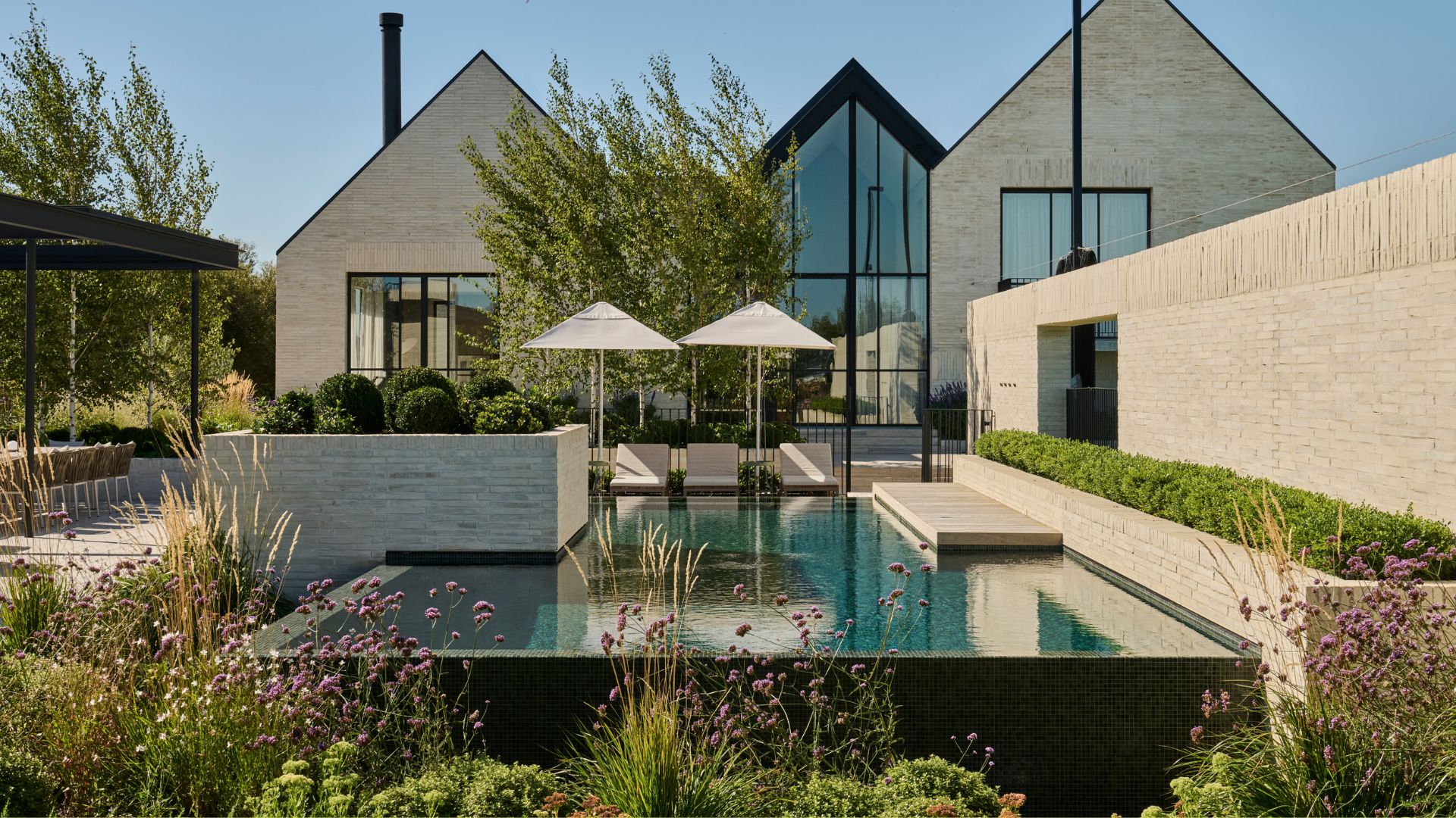 A large outdoor space with a pool, a garden, and outdoor parasols
