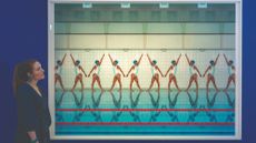 A visitor looks at Mária Švarbová's photograph of identical synchronised swimmers making the same repeated shape on a poolside