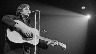 Johnny Cash playing acoustic guitar on stage