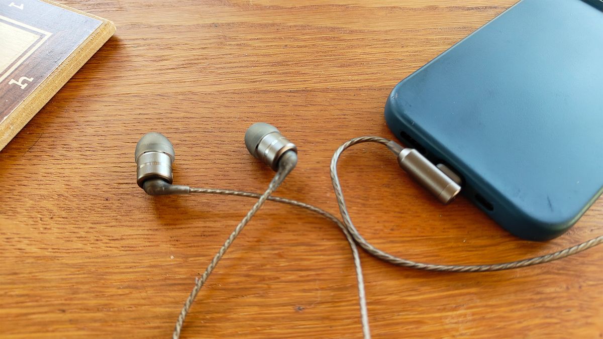 SoundMagic E80D wired in-ear headphones on wooden table plugged into smartphone