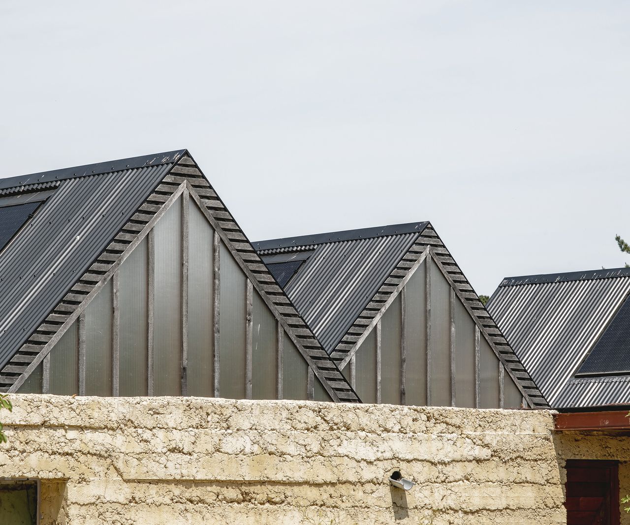 Three pitched roofs in a row made of black tin with solar panels