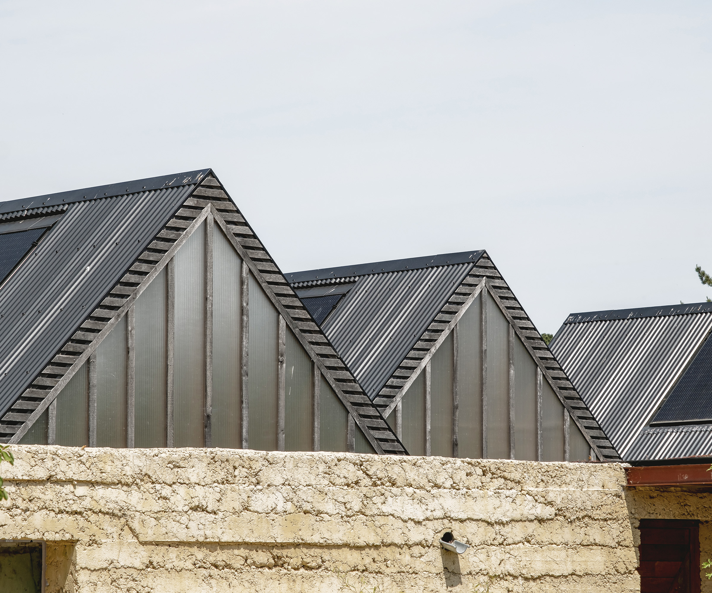 Three pitched roofs in a row made of black tin with solar panels