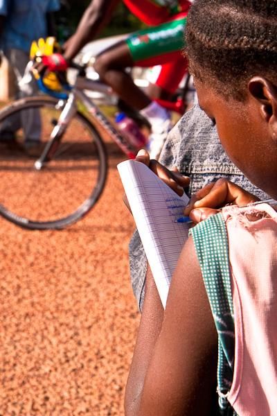 A schoolgirl takes notes for an assignment about the Tour du Faso.