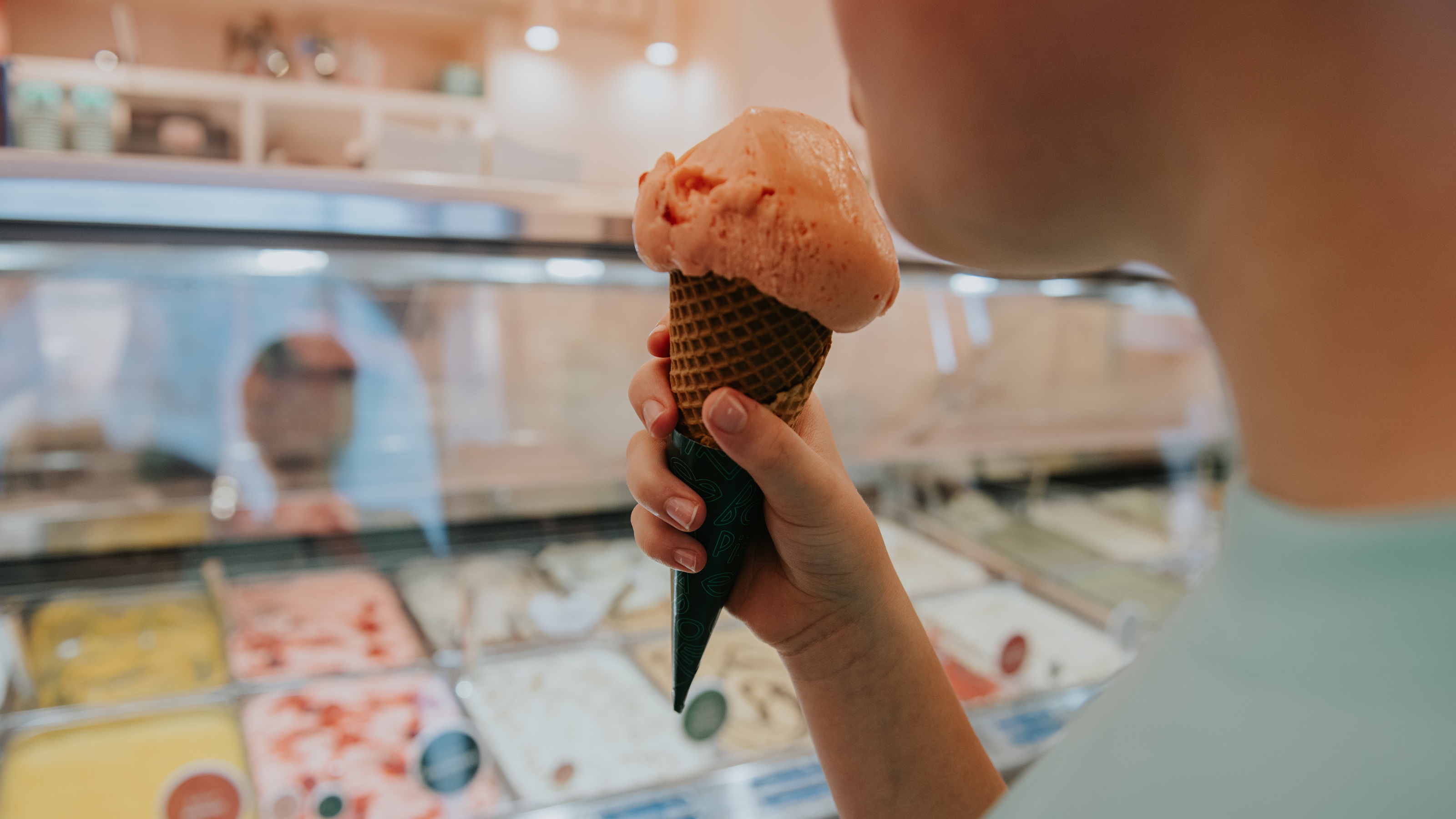 A young boy holds an ice cream cone in an ice cream parlor.