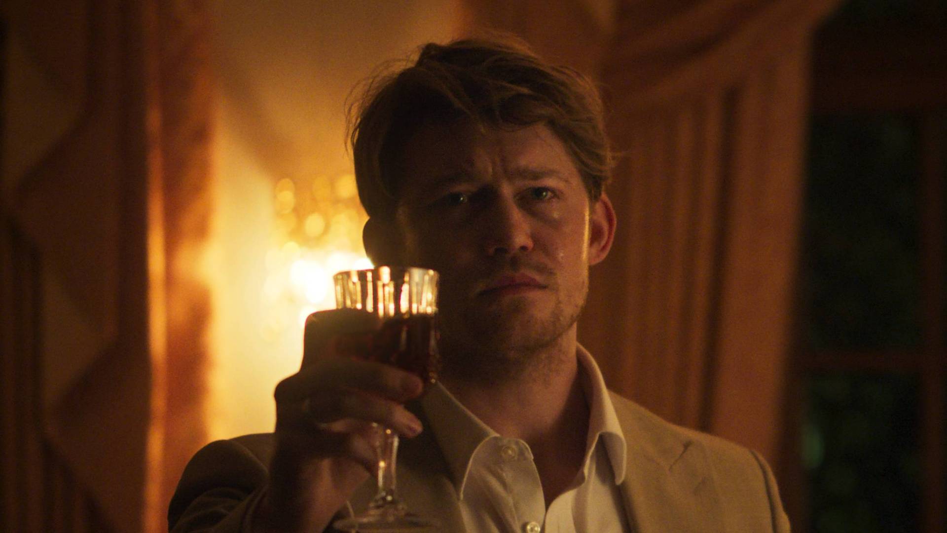 Joe Alwyn as Laertes in Hamlet, holding up a glass of wine