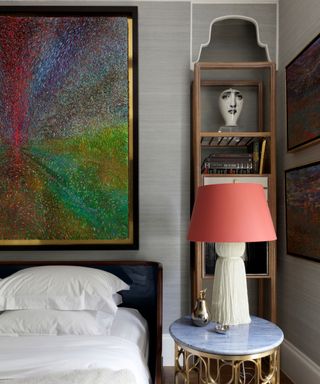 decorative bedroom with mixture of artworks and oversized bedside table lamp with pink shade