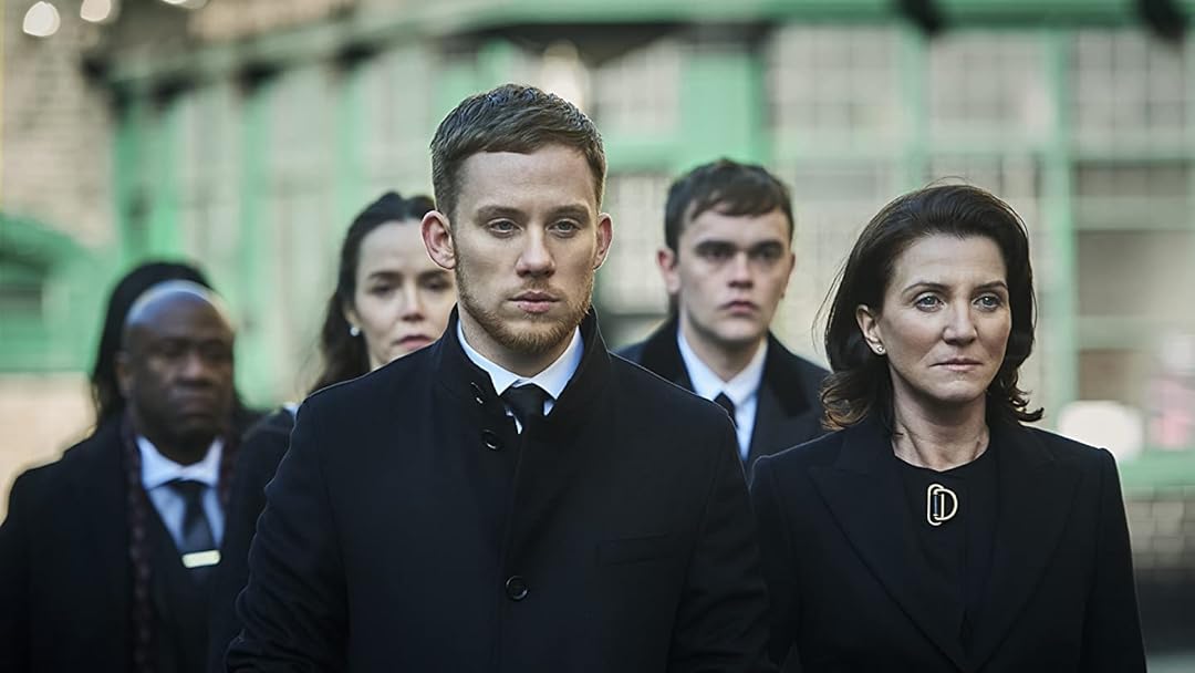 The Wallace family all wearing black standing together and looking at something off camera in Gangs of London.