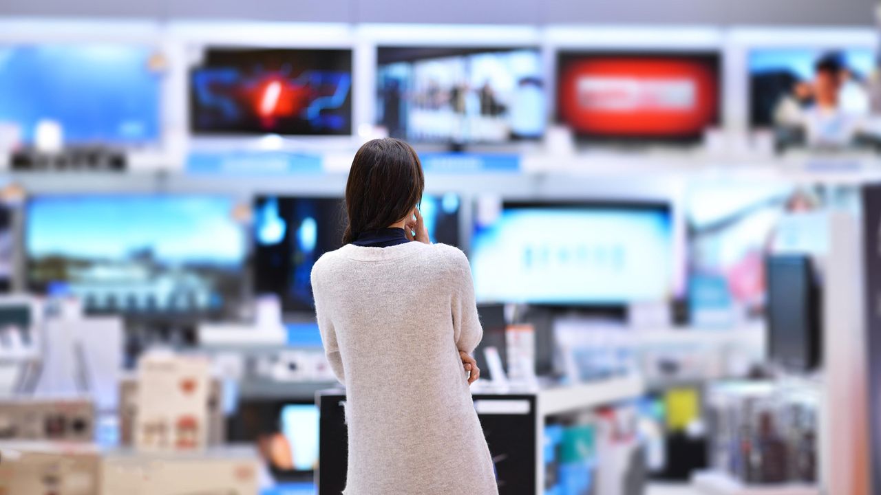 A woman ponders fancy TVs