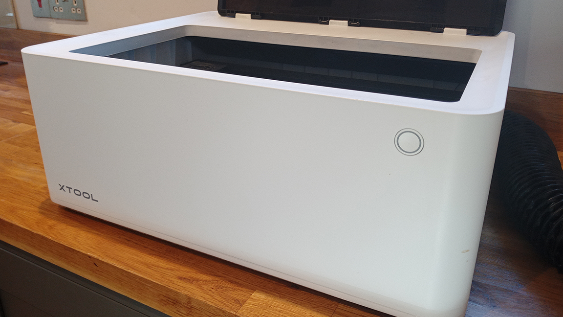 xTool M1 review; a white box on a wooden table with a transparent lid, which is open