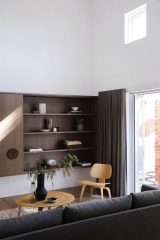 Minimalist living room with brown shelving, grey sofa and white walls