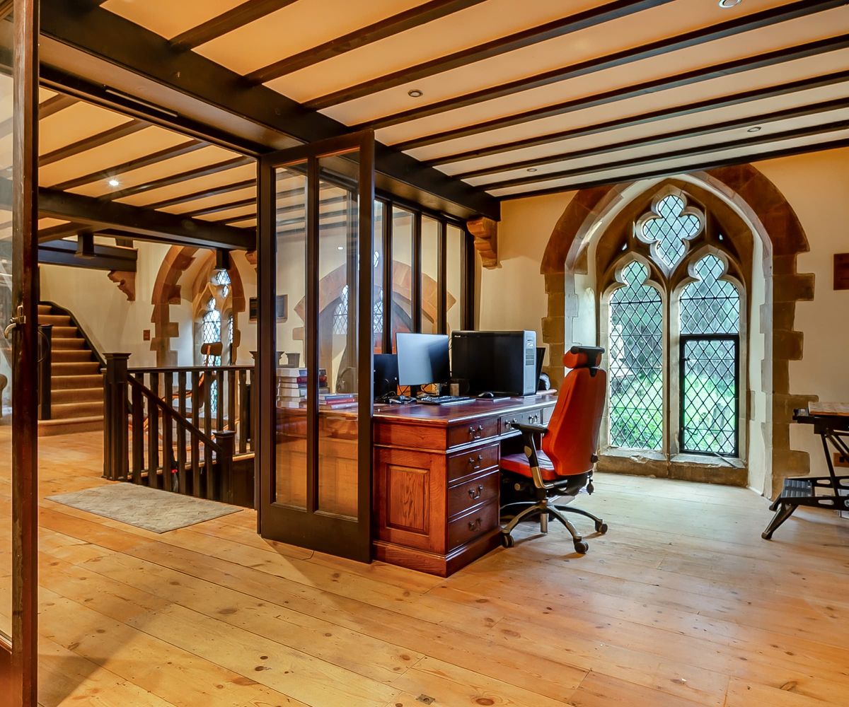 An office separated by a glass wall from a living room