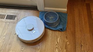 Narwal Freo X Plus robot vacuum and mop cleaning near a dog food bowl in reviewer's home