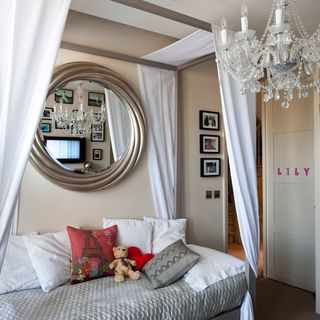bedroom with round mirror and chandelier