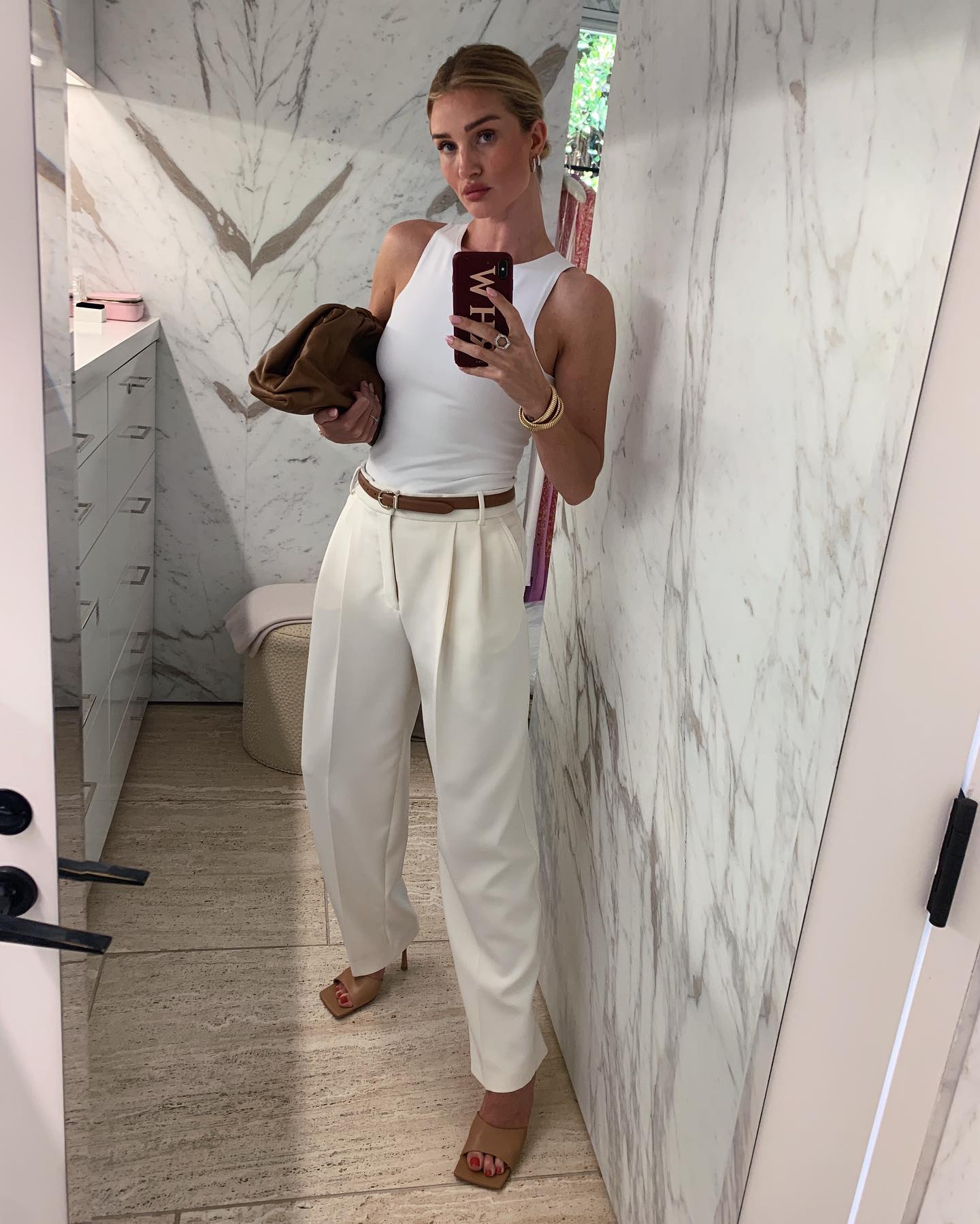 An image of @rosiehw wearing a white tank top with tailored trousers.