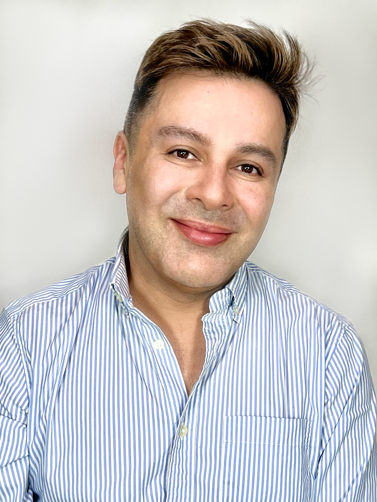 a headshot of a man wearing a blue shirt in front of a white background