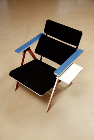 Looking over a chair with a black base, wood frame, blue coated tops of each arm. Two black rectangular back support elements.