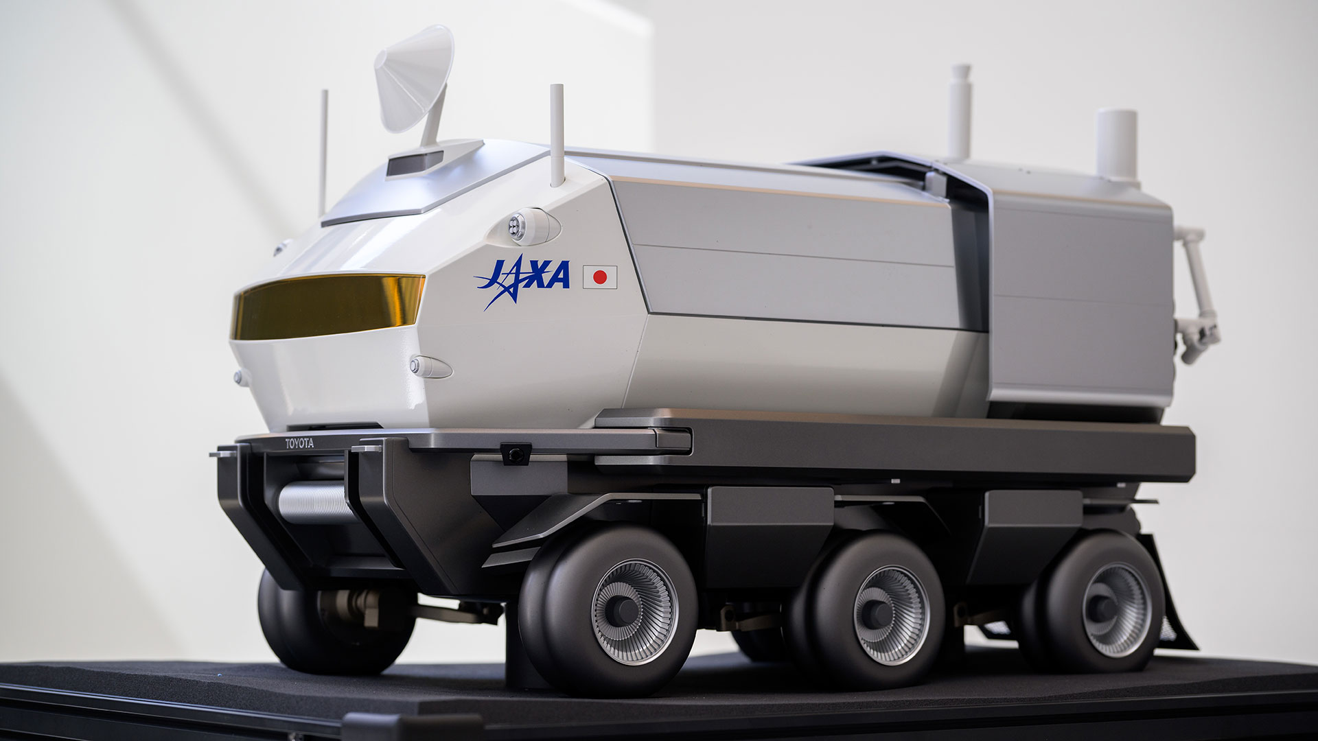 a model of a large, six-wheeled white moon rover rests on a table