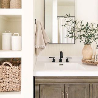 Modern bathroom with white shelving, wooden cabinet, and black faucets
