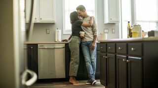 Male and female couple standing in the kitchen hugging