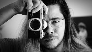 Black-and-white image of James Artaius holding an OM System OM-3