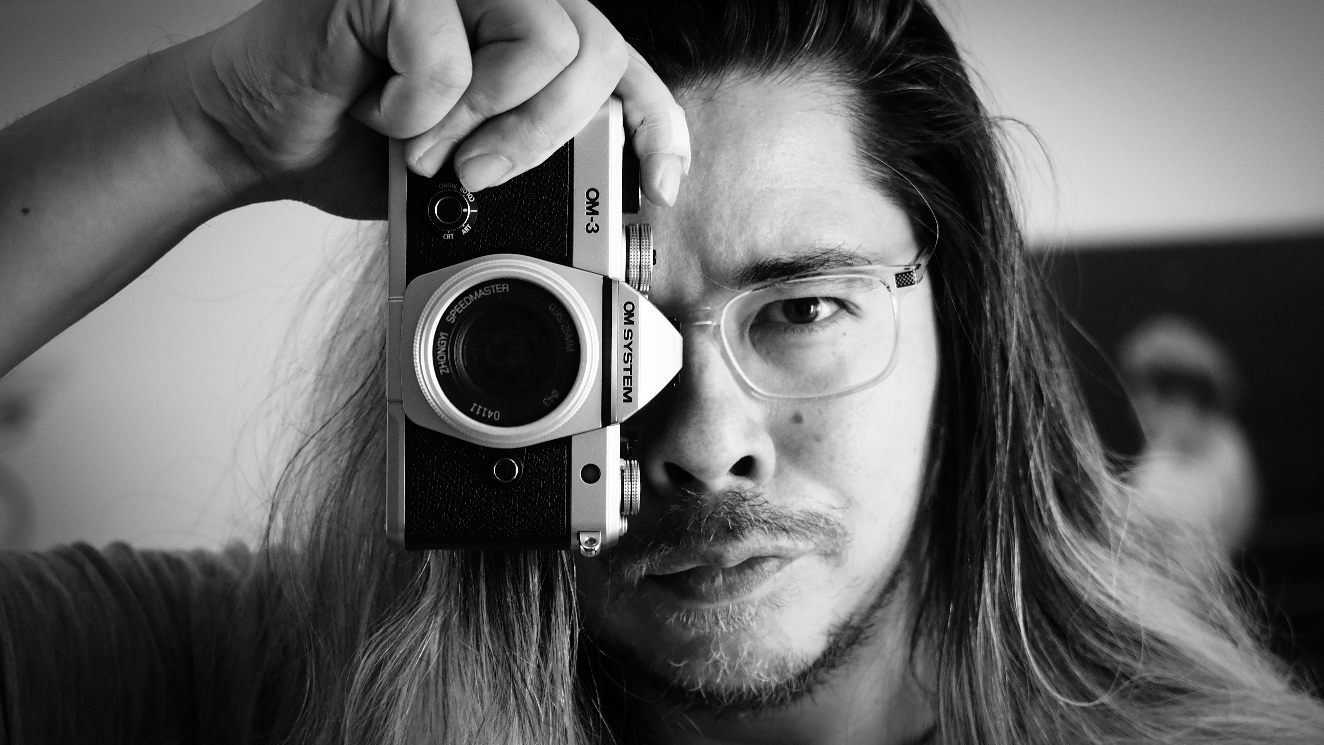 Black-and-white image of James Artaius holding an OM System OM-3