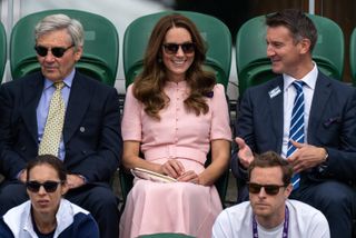 Kate Middleton in a pink dress sitting watching tennis