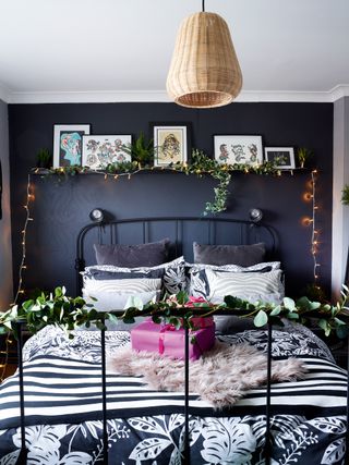 Dark grey bedroom with iron bed and decorated for christmas with faux greenery