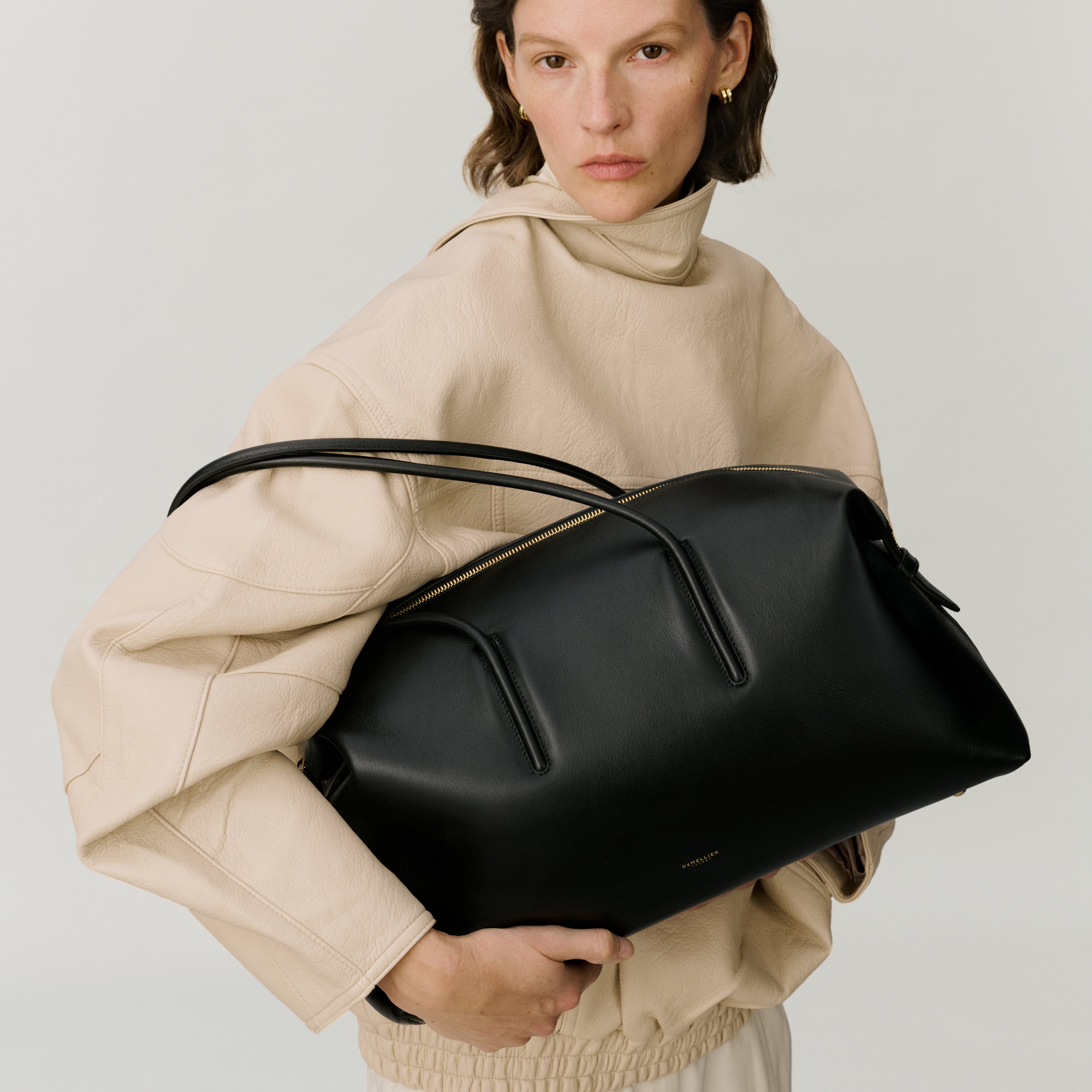 Woman wears leather skirt, black heels and carries black leather tote bag