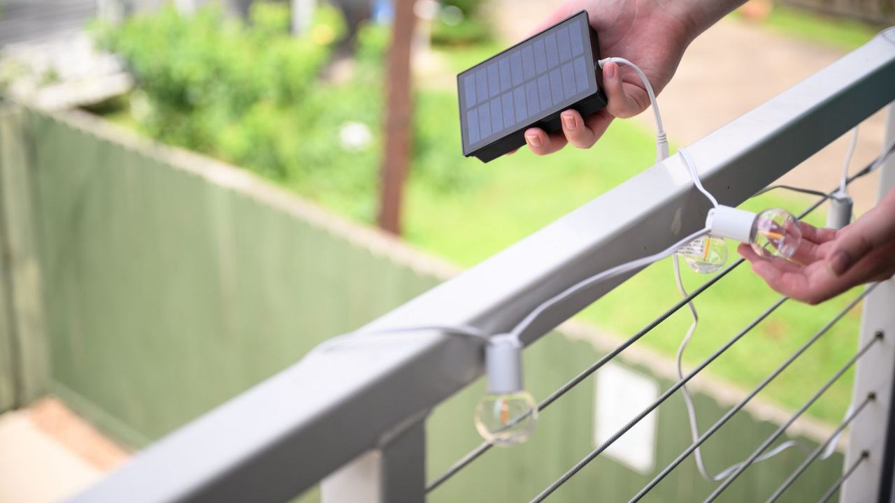 Hands placing solar string lights on a railing 