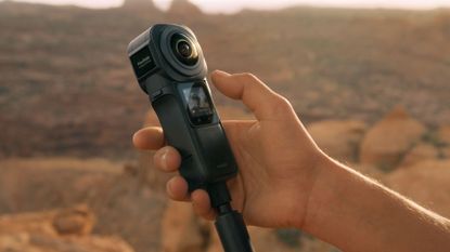 Person holding Insta360 ONE RS 1-inch 360 Edition action camera in rocky landscape