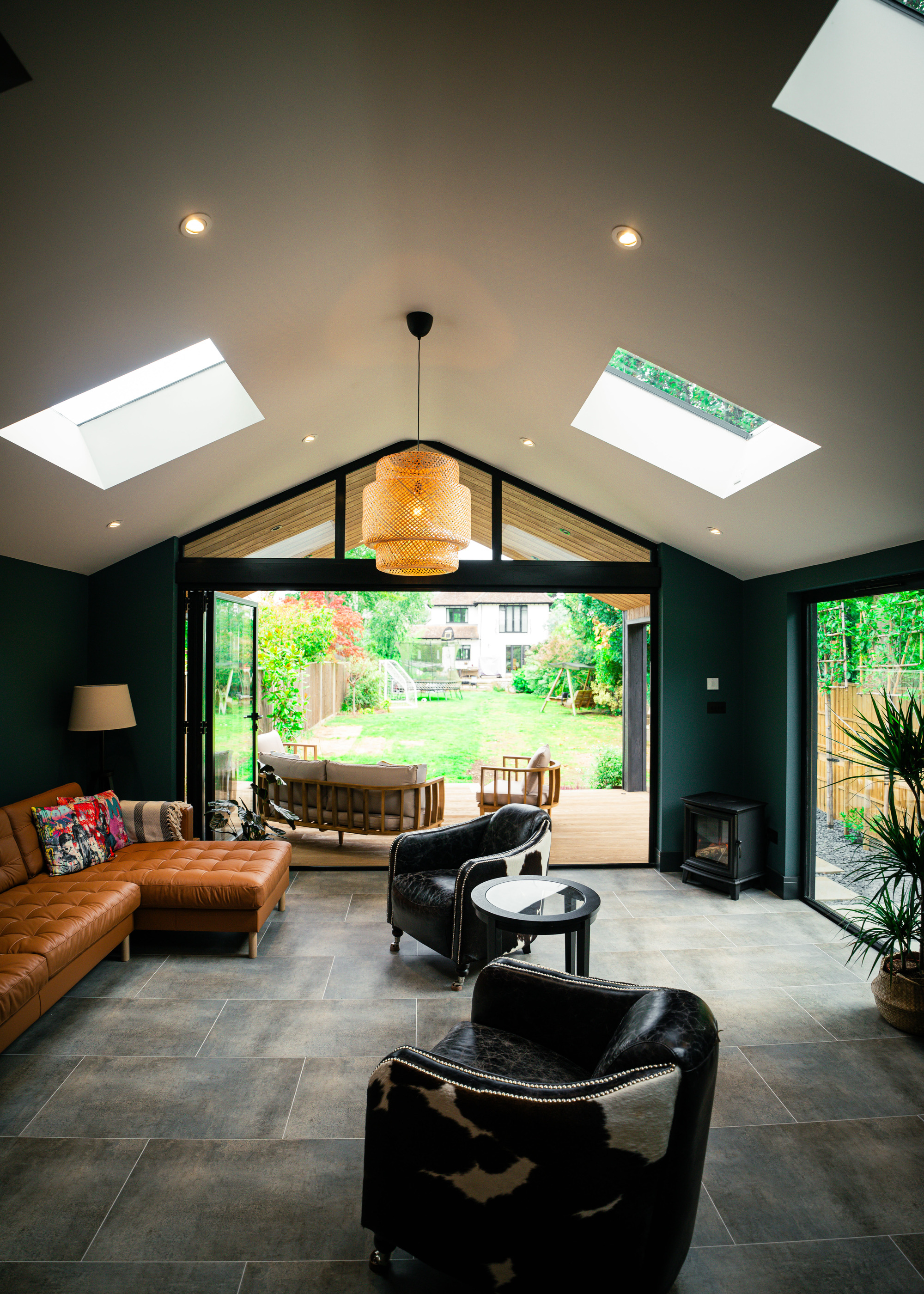 the interior or a large garden room with tan L-shaped sofa and cowskin tub chairs