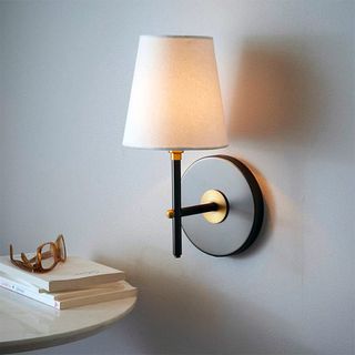 room with wall lamp on white wall and round white table